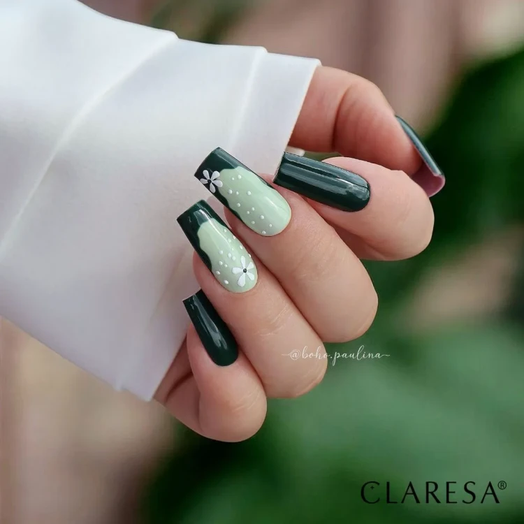 Claresa lakier hybrydowy "Autumn Crush 4". Stylizacja manicure na długich paznokciach z użyciem lakieru hybrydowego. Wzór kwiatków, kropek i french. Biały rękaw. Rozmazane tło w odcieniu zielonym.