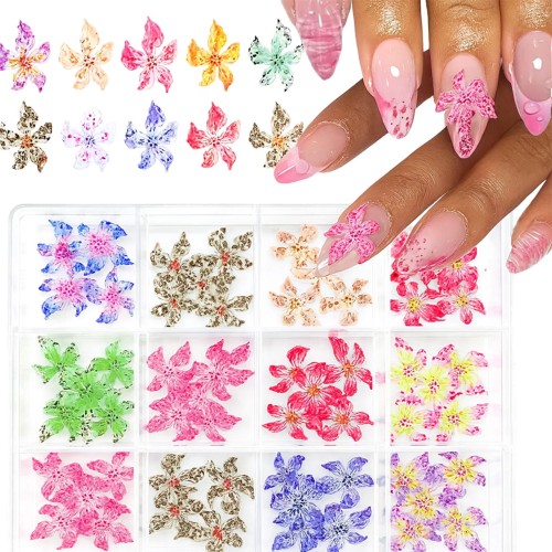 Clavier ozdoby do paznokci akrylowe kwiatki 3D w kasetce nr 85. Różne kolory: czerwone, żółto-różowe, żółto-fioletowe, pomarańczowe, niebieskie, fioletowe, zielone, różowe. Długie, różowe paznokcie przyozdobione produktem. Spakowane w kasetkę.