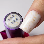 Pomalowany długi paznokieć kauczukową bazą Molly Lac ze złotymi płatkami flakes rubber base milk &amp; gold. HEMA FREE. Szklana buteleczka.